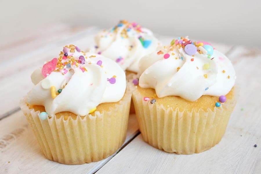 Vanilla cupcakes topped with icing and sprinkles
